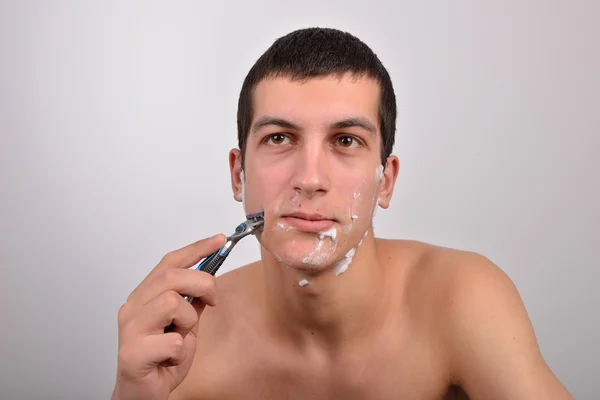 Bonito jovem com lotes de creme de barbear em seu rosto prepar — Fotografia de Stock