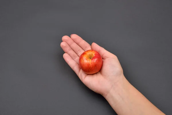 Hand van een vrouw met een rode frisse appel geïsoleerd op zwarte rug — Stockfoto