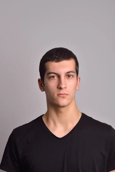 Портрет серйозного молодого чоловіка, що стоїть на сірому фоні — стокове фото