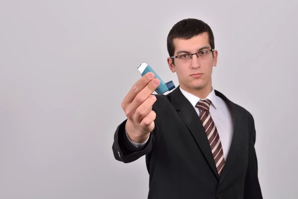 Young business man holding an asthma inhaler to handle problems — Stok fotoğraf