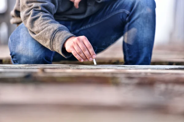 Hand eines jungen Mannes, der Zigaretten auf einer alten Brücke löscht. con — Stockfoto