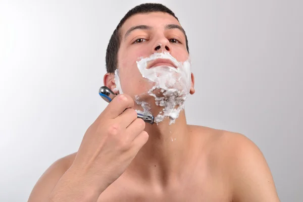 Bello giovane uomo con un sacco di crema da barba sul viso prepar — Foto Stock