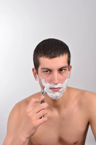 Bonito jovem com lotes de creme de barbear em seu rosto prepar — Fotografia de Stock