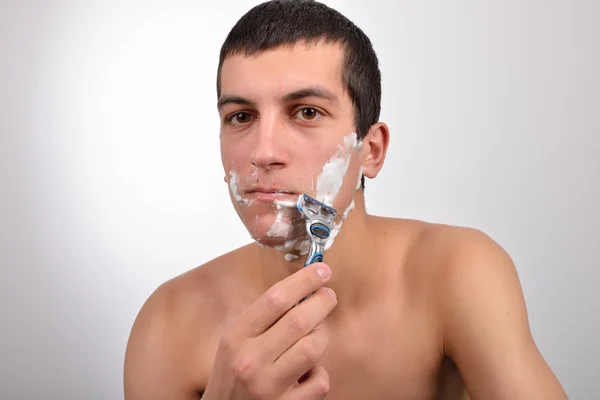 Bello giovane uomo con un sacco di crema da barba sul viso prepar — Foto Stock