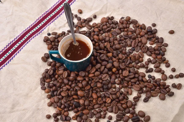 Granos de café tostados con taza y cuchara sobre fondo de yute. ¡Mamá! —  Fotos de Stock