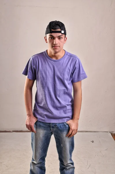 Handsome young man with backwards cap on his head posing in stud — Stock Photo, Image