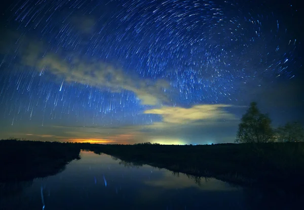 Un beau ciel nocturne, la Voie lactée, les sentiers étoilés en spirale et les arbres — Photo