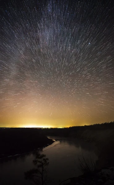 Un hermoso cielo nocturno, la Vía Láctea, las huellas de estrellas y los árboles — Foto de Stock