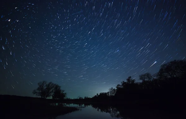 Krásná noční oblohy, spirálové stopy hvězd a Les — Stock fotografie