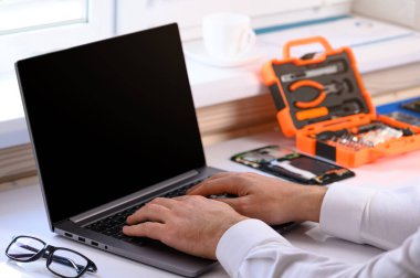 Akıllı telefon tamir kursları. Masada bir bilgisayar ve parçalanmış bir tablet var. Çevrim içi öğrenim