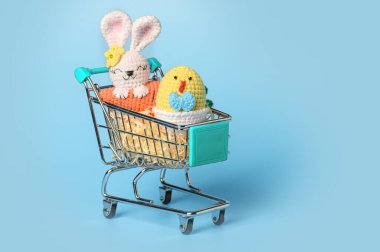 Mavi arka planda, alışveriş arabasında paskalya tavuğu. Mutlu Paskalyalar. Paskalya indirimi kavramı.