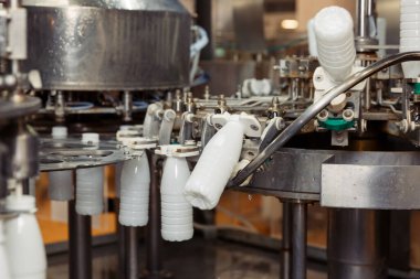 Fabrikadaki plastik şişelere süt dolduruyor. Süt ürünleri fabrikasında.