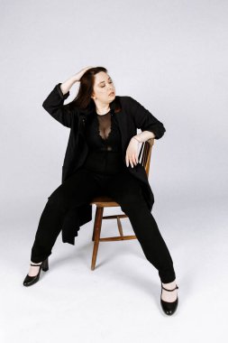 Kız seksi bir kostümle bir sandalyede oturuyor. Güzel model. fa