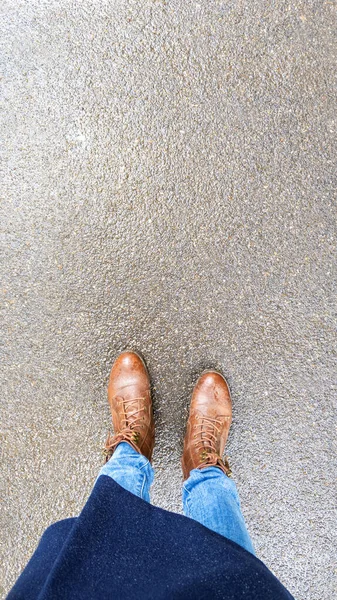 Top view selfie of woman feet in brown autumn boots on wet asphalt after rain. — Stock Photo, Image