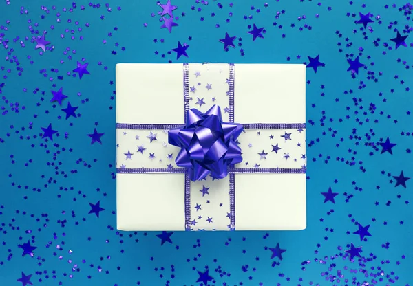 Caja de regalo y estrellas sobre fondo azul. Colocación plana monocromática. — Foto de Stock