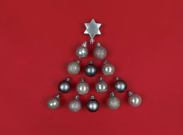 Forma de árvore de Natal feita com bugigangas de decoração em um papel vermelho. — Fotografia de Stock