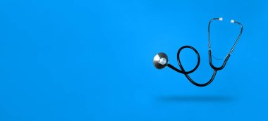 Levitating stethoscope on blue background and shadow under it with copy space. Stock photo. clipart
