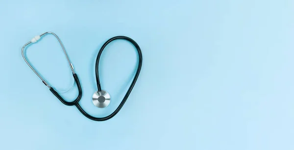 Black stethoscope on soft blue background. Simple flat lay with copy space. — Stock Photo, Image