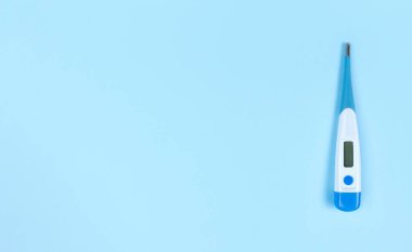 Kopyalama alanı olan mavi arkaplan üzerindeki elektronik termometre.