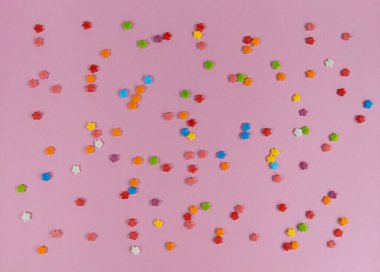 Pembe bir arka planda renkli tatlı konfeti çiçekleri.