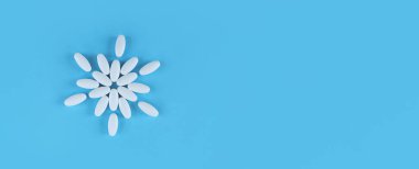 Fotokopi alanı olan mavi bir zemin üzerinde beyaz tabletlerden yapılmış çiçek şekli.