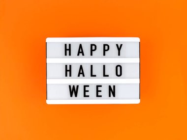 Turuncu arka planda Mutlu Cadılar Bayramı yazan ışık kutusu.