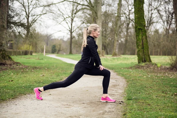 Woman stretching her legs in the park — Stock Photo, Image