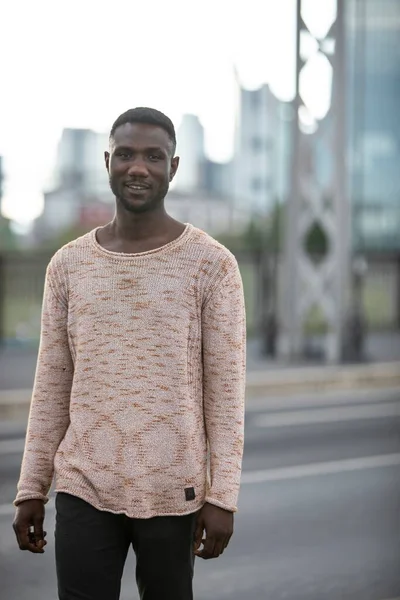 Handsome black man wearing sweater outdoors in city. Portrait. Three quarter length. Looking at camera.