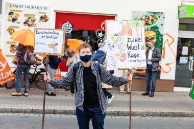 Gottingen, Almanya. 2020 sonbaharında. Gelecek için cuma günleri. Genç, beyaz bir adam protesto sırasında sokakta pankart tutuyor. Üç çeyrek uzunluk. 