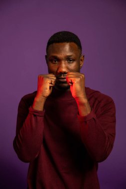 Dövüş pozisyonunda genç siyahi bir adam kameraya bakıyor. Orta boy. İzole edilmiş arkaplan. 