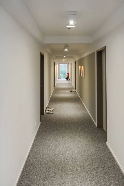 Long building corridor with window at vanishing point end. Vertical.