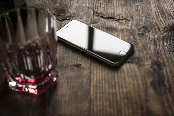 Smartphone on wooden table with whiskey — Stock Photo, Image