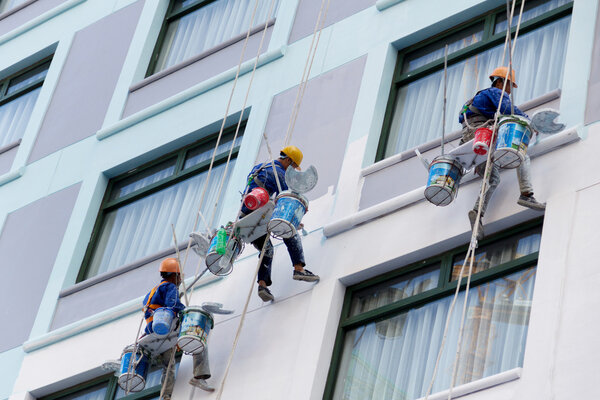 Рабочие рисуют цвет в высотных зданиях
.