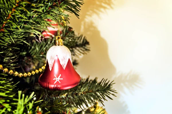 Red Christmas bell on the Christmas tree. Nice shadow on the white wall. Copy space on the right side.