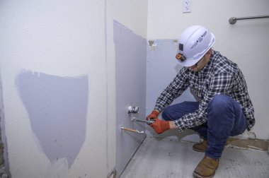 Tesisatçı tadilat yapılan bir banyoya su vanası yerleştiriyor.