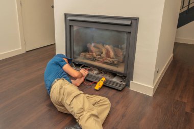 Service technician working on a gas fireplace inside of a residential home clipart