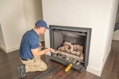Service technician repairing a gas fireplace in a home clipart