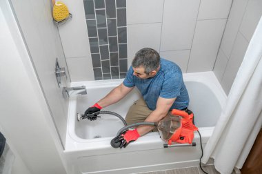 Tesisatçı yılanıyla banyo küvetini temizliyor.