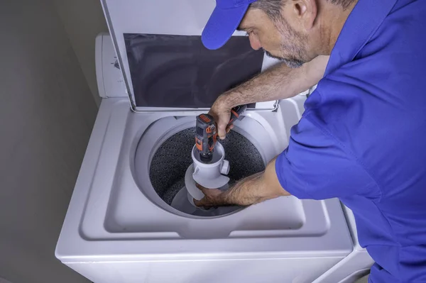 Mavi Üniformalı Bir Cihaz Teknisyeni Kablosuz Matkap Kullanarak Çamaşır Makinesine — Stok fotoğraf