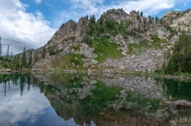 Dağlar Grand Teton Ulusal Parkı 'ndaki Surprise Gölü' ndeki sakin bir alp gölünden yansıyor.