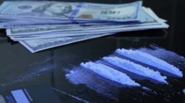 Bağımlı, siyah masadan kokain ya da eroin beyaz uyuşturucu tozu çekiyor. Uyuşturucu bağımlısı uyuşturucu kullanıyor. Adam para bankasında amfetamin kokusunu alıyor.