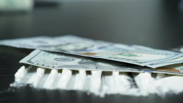 Bankbiljetten van 100 dollar storten op tafel met cocaïne of witte poederdrugs. Geld en kruit tegen zwarte achtergrond. Illegale drugs en zwart geld. Lijnen van cocaïnepoeder — Stockvideo