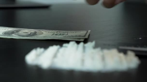 Siyah masanın üzerinde kokain tozları ve insanlar bize arka planda dolar sayıyor. Beyaz toz şeritleri. Dolar banknotlarının yanında kokain ya da beyaz uyuşturucu tozu. Madde bağımlılığı kavramı — Stok video