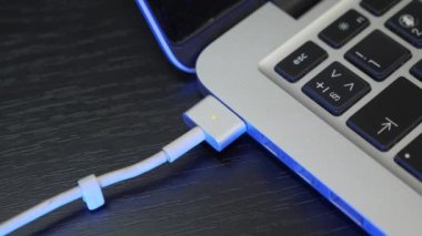 Adam USB tip C konnektörü için dizüstü bilgisayarın bağlantısını kesiyor. El, beyaz kabloyu bilgisayara bağlıyor