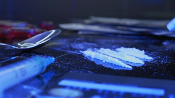 Чоловік нюхає лінії кокаїну через загорнуту банкноту доларів на чорному тлі з наркотичними речовинами та шприцом. Залежність, концепція зловживання речовинами. Порошковий препарат висмоктується через солому — стокове відео