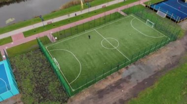 Yeşil yapay futbol sahasında futbol oynayan insanlar. Erkekler dışarıda, gezinti sahasında futbol oynuyor.