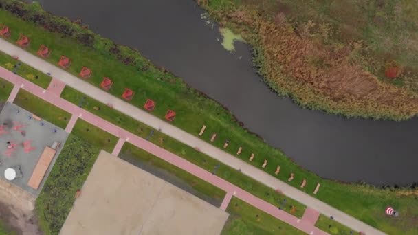 Vista superior de las zonas de voleibol, fútbol y boxeo en el paseo verde de la ciudad con un pequeño río en otoño — Vídeos de Stock