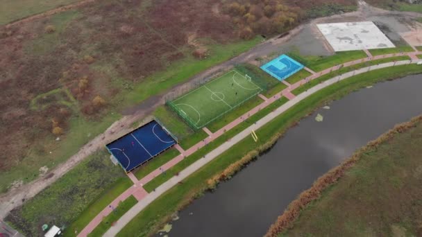 Зеленое искусственное футбольное поле на городской набережной. Крутящийся вид на футбольную зону на набережной возле реки — стоковое видео