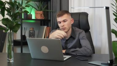 Yorgun iş adamı akşamları ofiste çalışıyor. Çok çalışan adam çalışma masasında oturuyor ve dizüstü bilgisayar kullanıyor. Erkek, gözlüğünü çıkarıyor, iş yerinde yorgun ve iş yüzünden sıkıntılı.