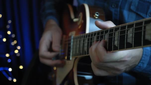 A gitáros kezei gitárhúrokon játszanak, közelről. Férfi gitáros szólógitár szerepet játszik a felvétel hangstúdió sötétben fényekkel — Stock videók